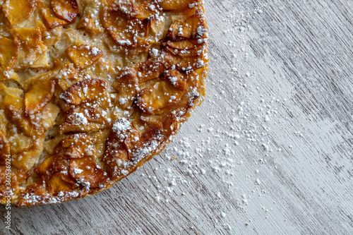 Obraz na płótnie Homemade baking. Freshly baked apple pie on a light wooden background sprinkled with icing sugar. w salonie