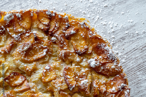 Obraz na płótnie Homemade baking. Freshly baked apple pie on a light wooden background sprinkled with icing sugar. w salonie