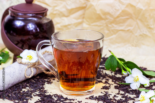 Fresh organic aromatic herbal tea in the glass cup with white jasmine flowers on light background.