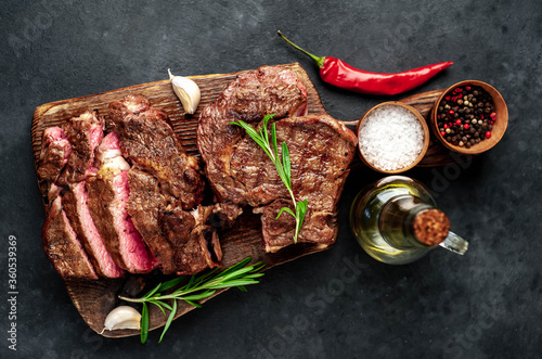 Two grilled beef steaks with spices on a stone background