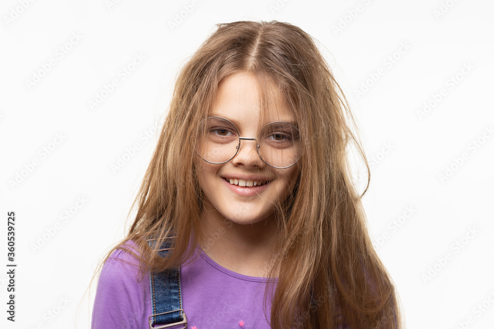 Portrait of a cheerful tousled long-haired girl of eleven years in glasses Portrait of a cheerful tousled long-haired girl of eleven years in glasses