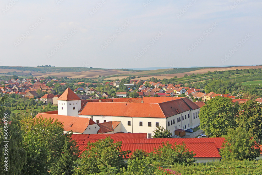 Cejkovice village in south Moravia region, Czech Republic. The view on the city and the castle with red roof surrounded by hills and vineyards. 