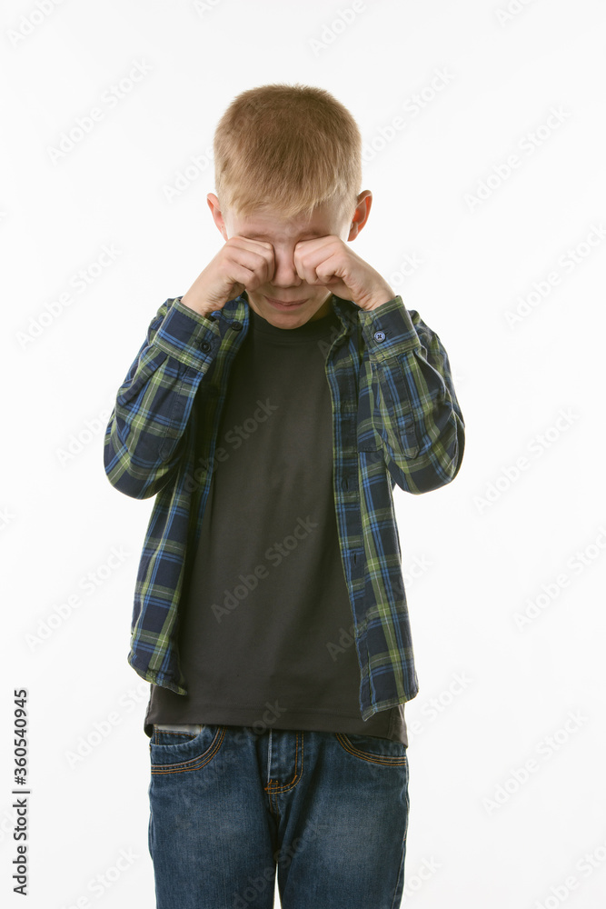 Crying boy rubs his eyes with his fists Crying boy rubs his eyes with his fists