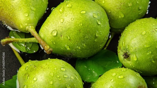 Green pears are splashed with drops of water as food background