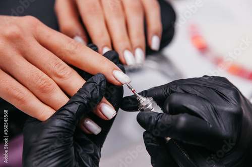 manicurist cuts nails in his beauty salon