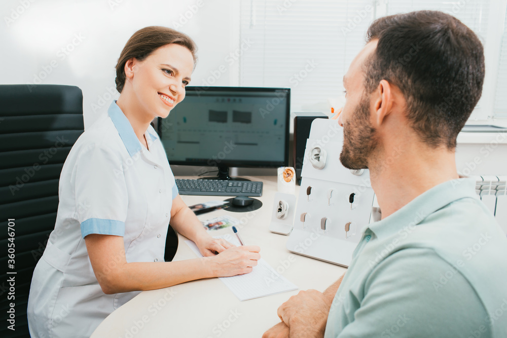 Consultation, an audiologist communicates with an adult man in a hearing clinic. Doctor and patient, diagnosis, and treatment of hearing. Consultation, an audiologist communicates with an adult man in a hearing clinic. Doctor and patient, diagnosis, and treatment of hearing.