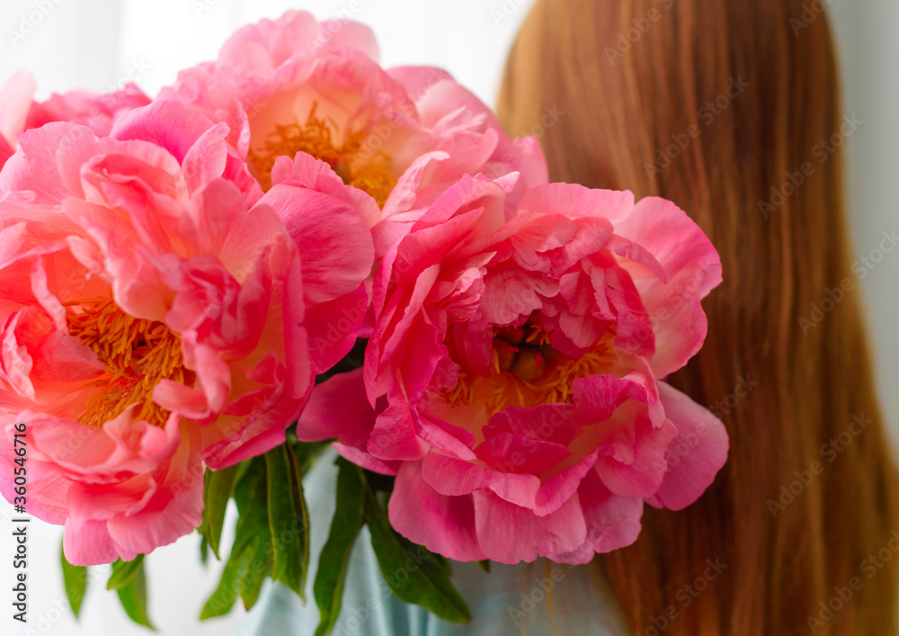 red-haired girl with a bouquet of pink peonies for her mother or grandmother
