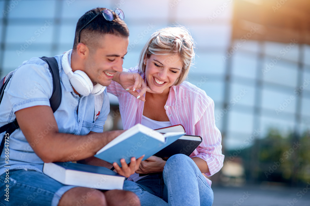 Young couple with books outdoors.