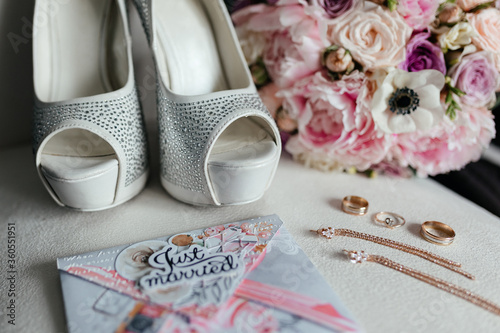 Bridal wedding heels, bouquet, card just married and gold ears and rings at the white background. Bridal preparation