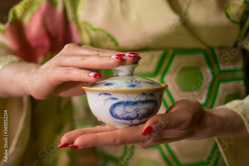 A girl in a green kimono with red manicure holds a white and blue bowl in her hands. Good for restaurants, posters, banners, flyers.
