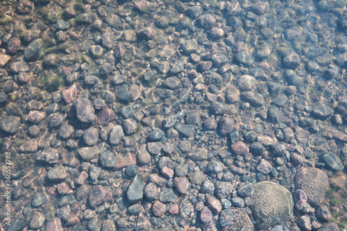 Stones beneath the clear water of a river. Top view.