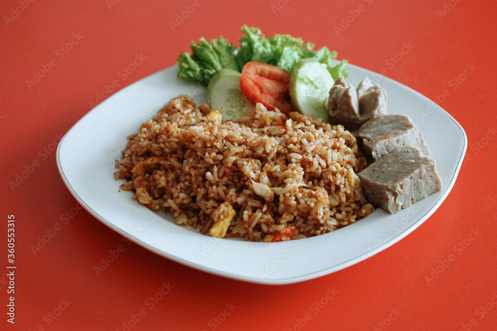 Indonesian fried rice with beef meatballs. fresh tomato lettuce and cucumber Indonesian fried rice with beef meatballs. fresh tomato lettuce and cucumber