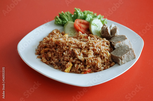 Indonesian fried rice with beef meatballs. fresh tomato lettuce and cucumber