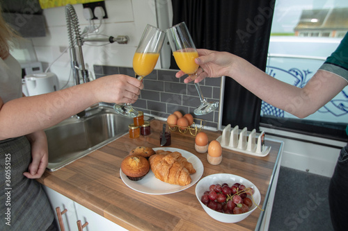A celebration breakfast is served in this trendy renovated camper van  includes eggs  croissants  orange juice etc served on wooden kitchen surface and grey tiled kitchen area