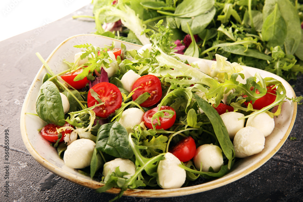 Mix fresh leaves of arugula, lettuce, spinach, beets for salad on table. Salad with tomato Mix fresh leaves of arugula, lettuce, spinach, beets for salad on table. Salad with tomato