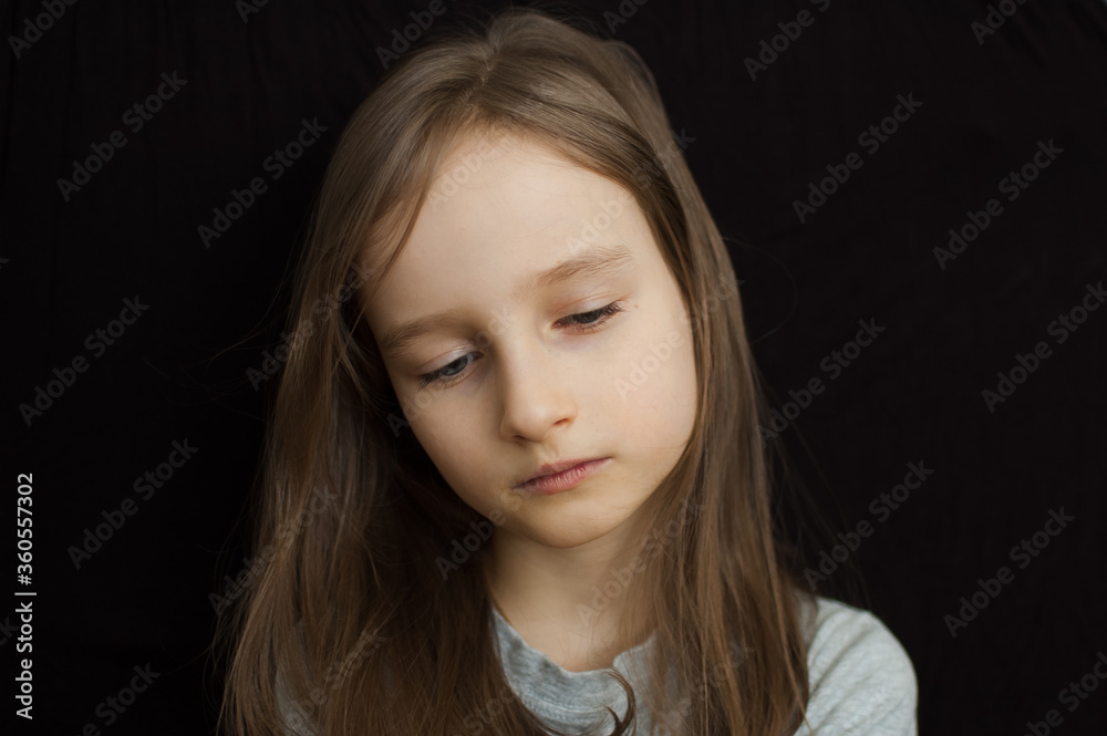 Portrait of a little sad girl with long blond hair and closed eyes on black background in studio Portrait of a little sad girl with long blond hair and closed eyes on black background in studio