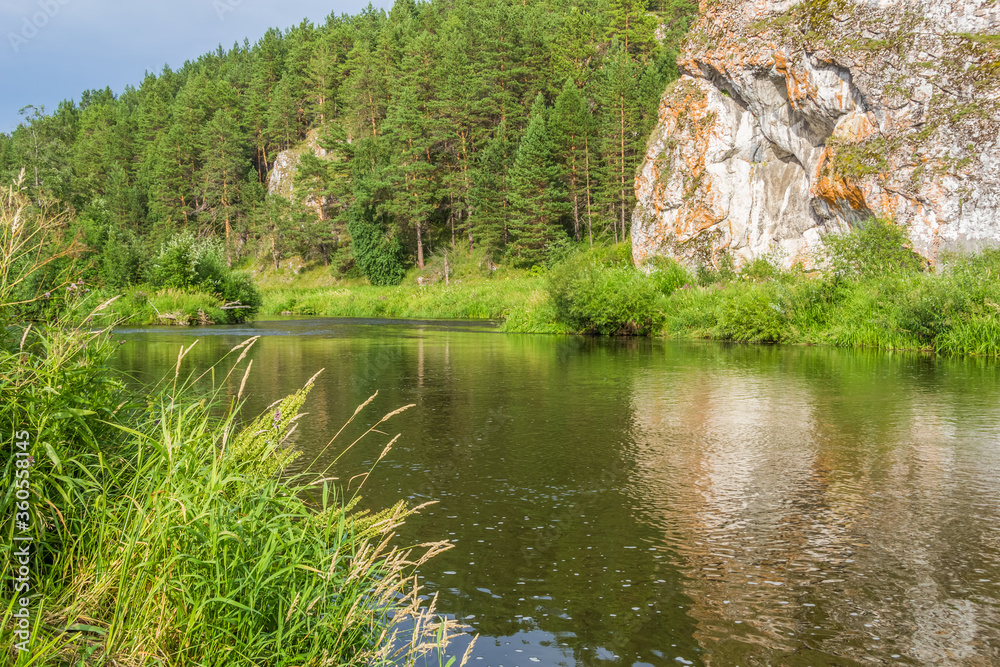 Picturesque landscape with forest, cliff and reflection in the river