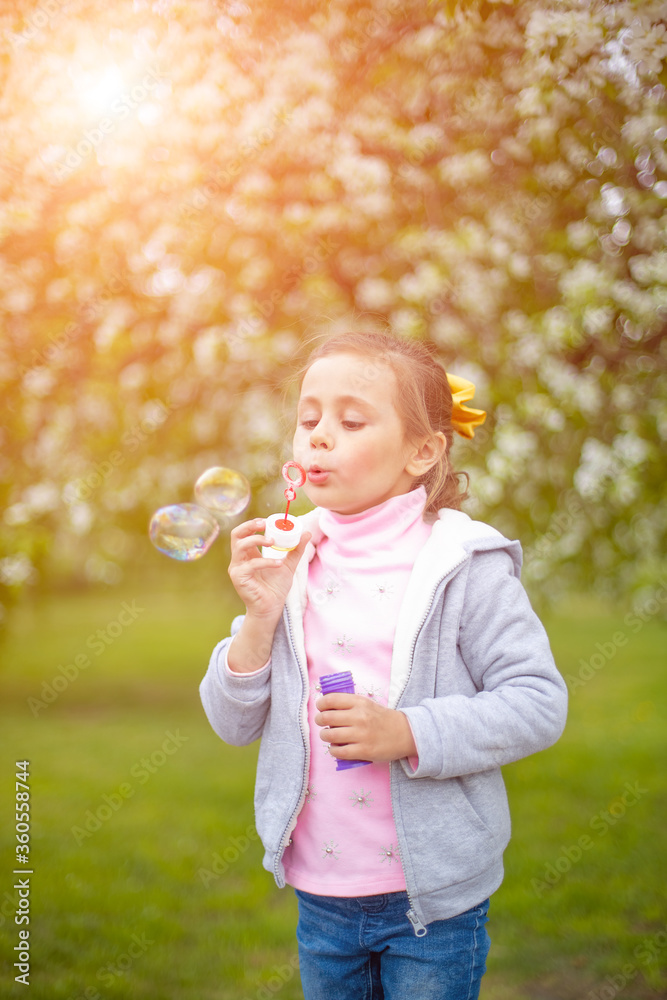 Beautiful little blonde girl, has happy fun cheerful smiling face, soap bubble blower.