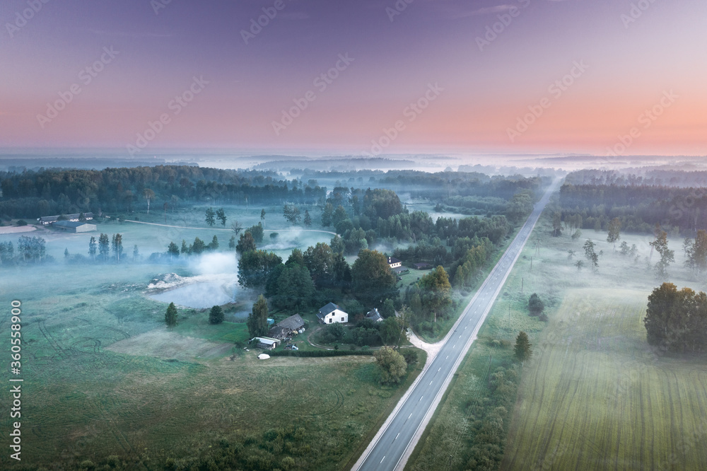 Highway going through meadow in mist surrounded by forest. Aerial view over picturesque landscape in fog at sunrise.
Highway going through meadow in mist surrounded by forest. Aerial view over picturesque landscape in fog at sunrise.