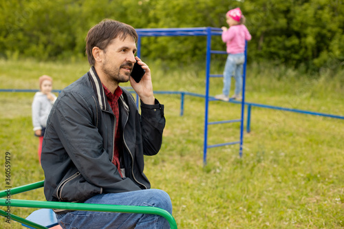 Obraz na plátne Dad talks by his phone and does not follow children in the playground