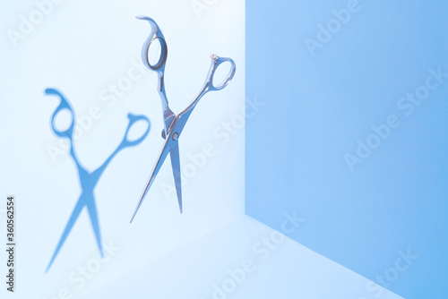 Hairdresser salon concept, Haircut accessories. Flying hairdresser tools scissors under trendy color background with copy space and hard light. Stylish Professional Barber Scissors