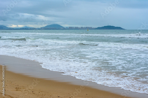 Cloudy day, sand deserted beach of the coast of Haitang Bay in South China Sea. Sanya, island Hainan, China. Nature Landscape.