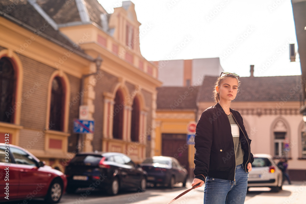 A young teenage caucasian girl walks her dog breed American Stafforshire Terrier on the street A young teenage caucasian girl walks her dog breed American Stafforshire Terrier on the street