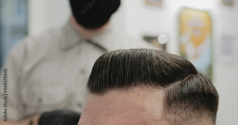 Retro haircut and hair styling in a barbershop. Side view.