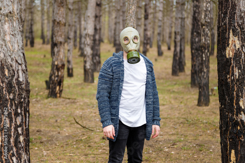 Man in gas mask standing in pine forest. Enviromental protection, ecology, Earth saving, pollution prevention and hope concept.