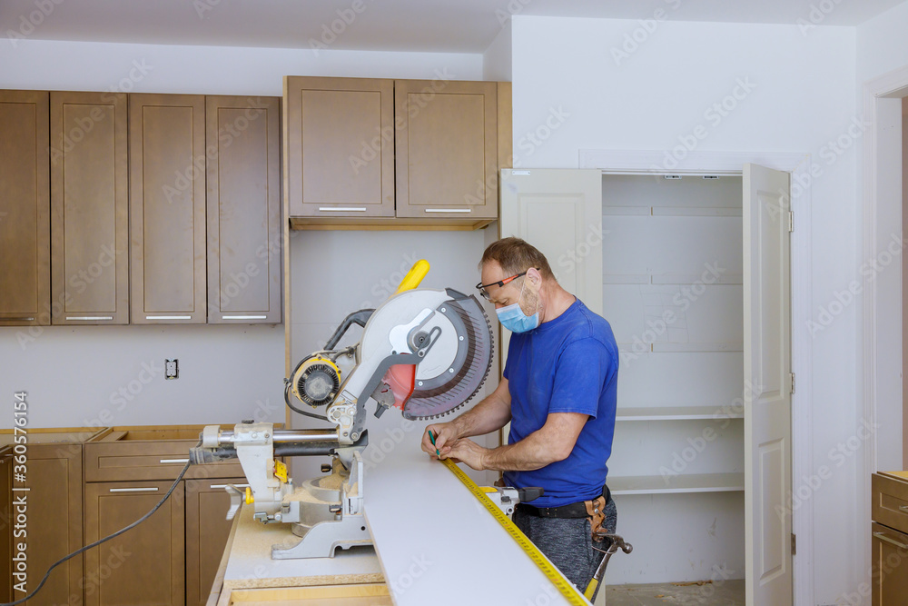 Worker protects himself from covid-19, man cut using circular saw rotating saw cutting wooden installation of in the kitchen of installation cabinets Worker protects himself from covid-19, man cut using circular saw rotating saw cutting wooden installation of in the kitchen of installation cabinets