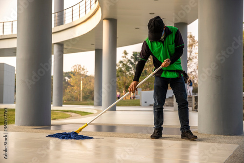 A  janitor man  cleaning  mopping floor in office building or walkway modern building.