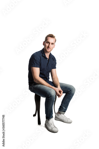 A picture of a European male sitting casually on a stool loving his weekend wearing casual clothes.