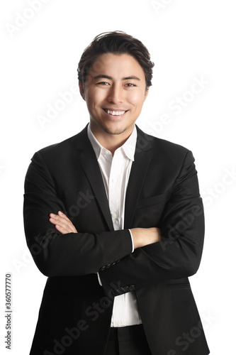 A vibrant and handsome Asian business
partner giving a confident smile wearing a black suit and
white collared shirt with his arms crossed against his chest
on white background.