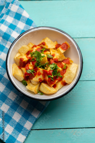 Spanish fried potatoes with sauce also called patatas bravas on turquoise background photo