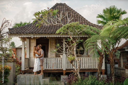 Love story. Romantic couple in relationship stand in front of wooden house and hug each other © Yevhenii