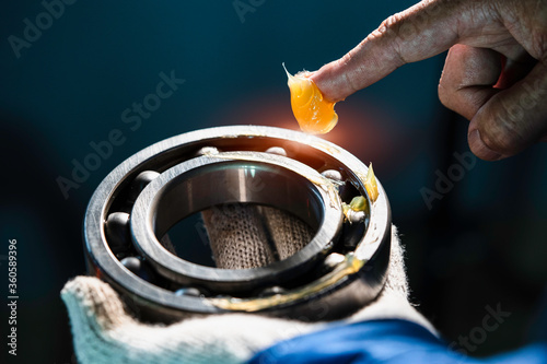 Mechanic is putting yellow grease in the into bearing, engineering and industrial concept. photo