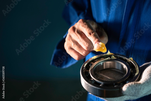Mechanic is putting yellow grease in the into bearing, engineering and industrial concept. photo