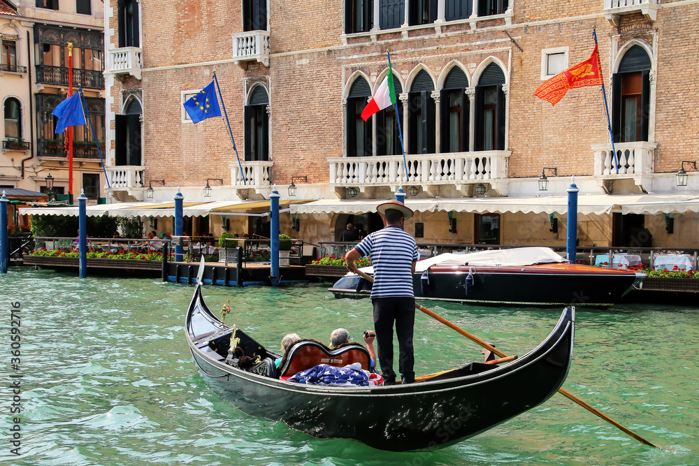 Gondolier rowing gondola with tourists on Grand Canal in Venice, Italy