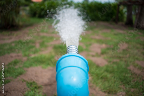 water sprinkler spraying water from blue pipe in the garden