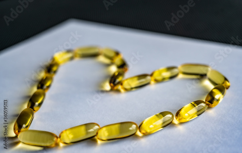 Yellow clear omega-3 gel capsules in the shape of a heart