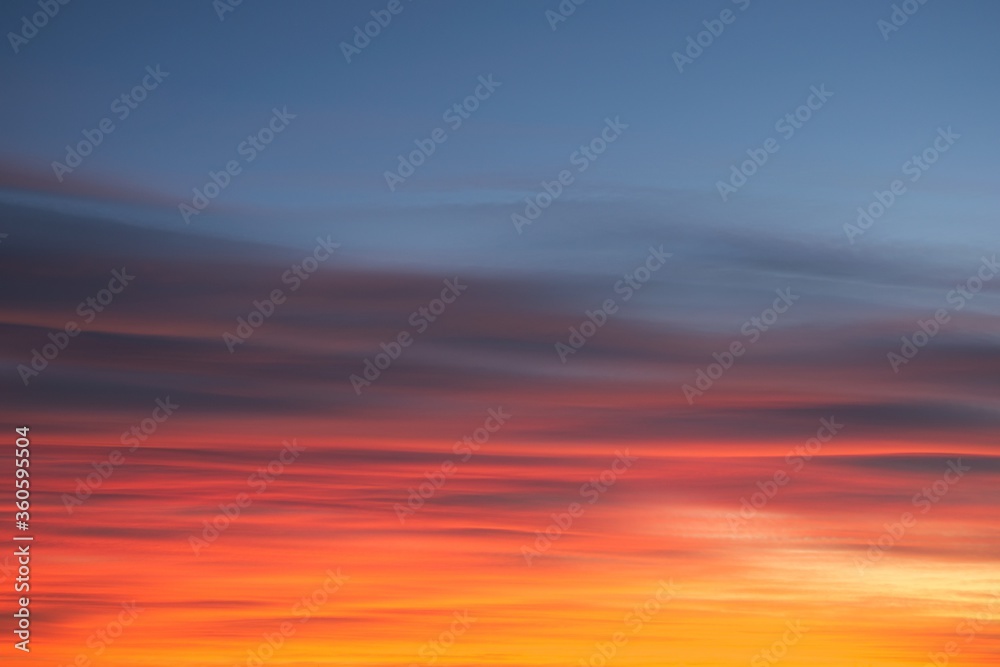 Intense, radiant orange cirrus clouds at dawn against a deep blue sky.
