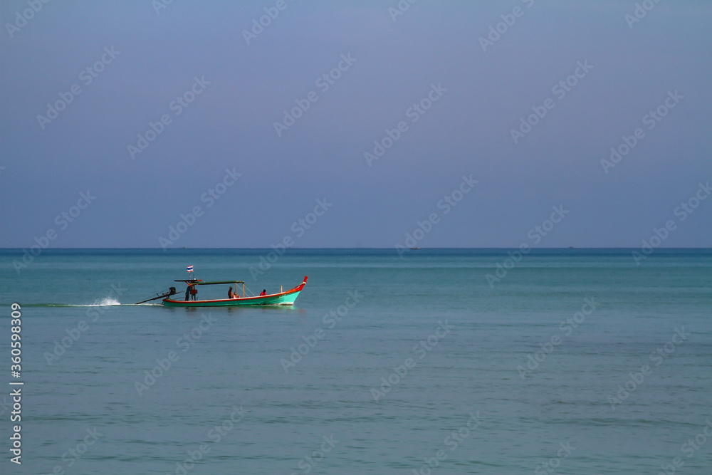 Traditional fishing boat in the tropical sea in Thailand with blue water and blue sky