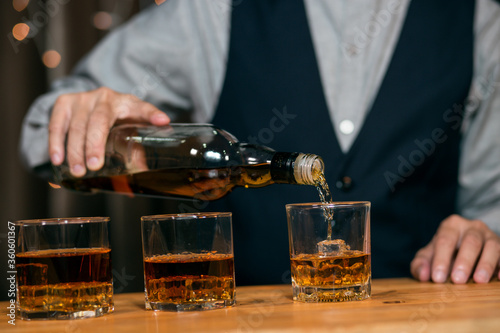 Barman pouring whiskey glass customers sit drink
