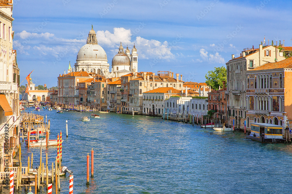 Panoramatic view on Grand Canal with basilica of Santa Maria della Salute in the background. Photo made from Ponte della Costituzione bridge. Bussy water-traffic, boats and small ships on the water.