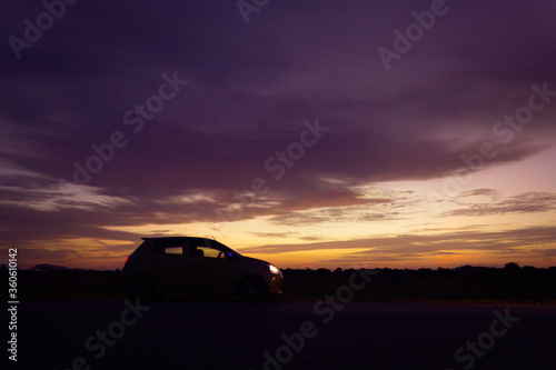 Silhouette car at road side and sunset road trip