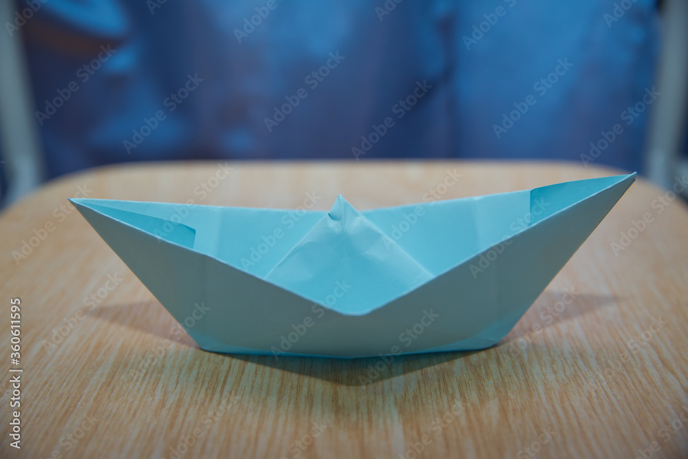 Leadership concept with blue paper ship leading among wooden . Blue paper boat on wooden background . Origami paper ship .