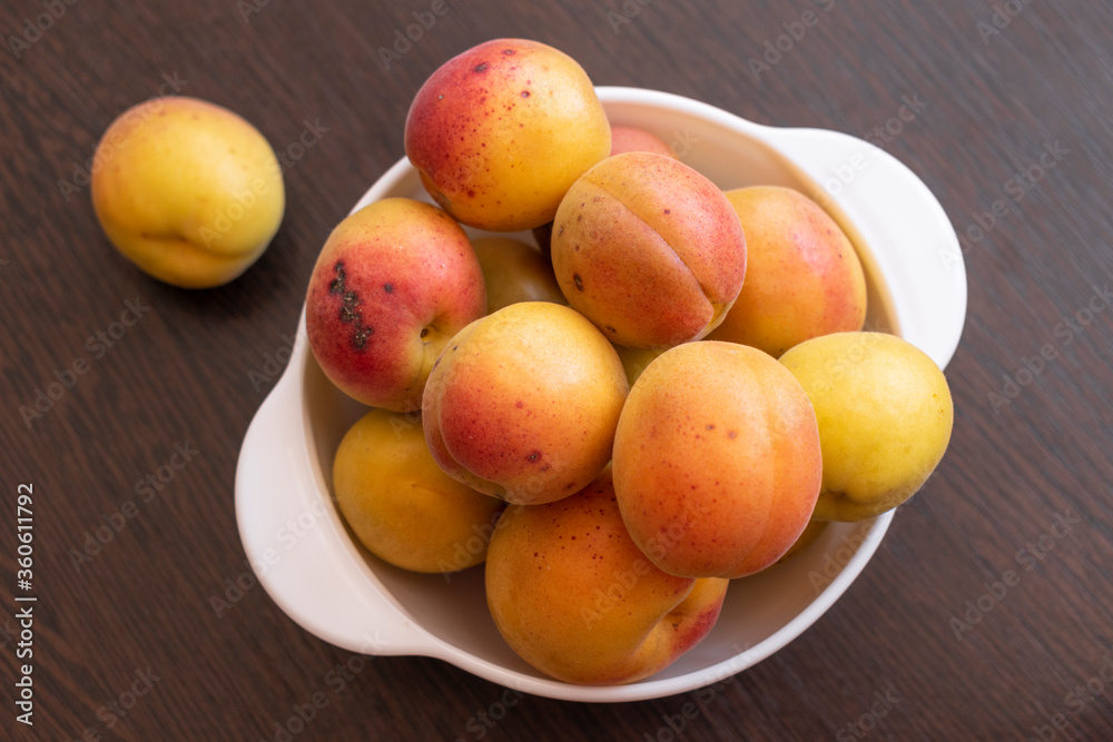 Ripe apricots in a white bowl on a brown table
Ripe apricots in a white bowl on a brown table