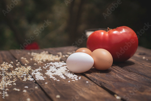 Cuban rice ingredients: tomato, rice and eggs on a wooden background