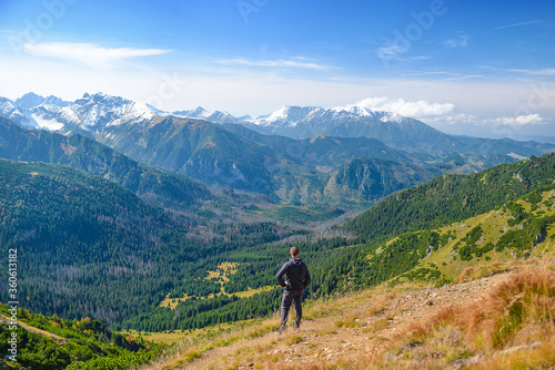 Hiker on the mountain crest enjoying the view. A man tourist on the ridge, seeing the panorama. Central Europe.