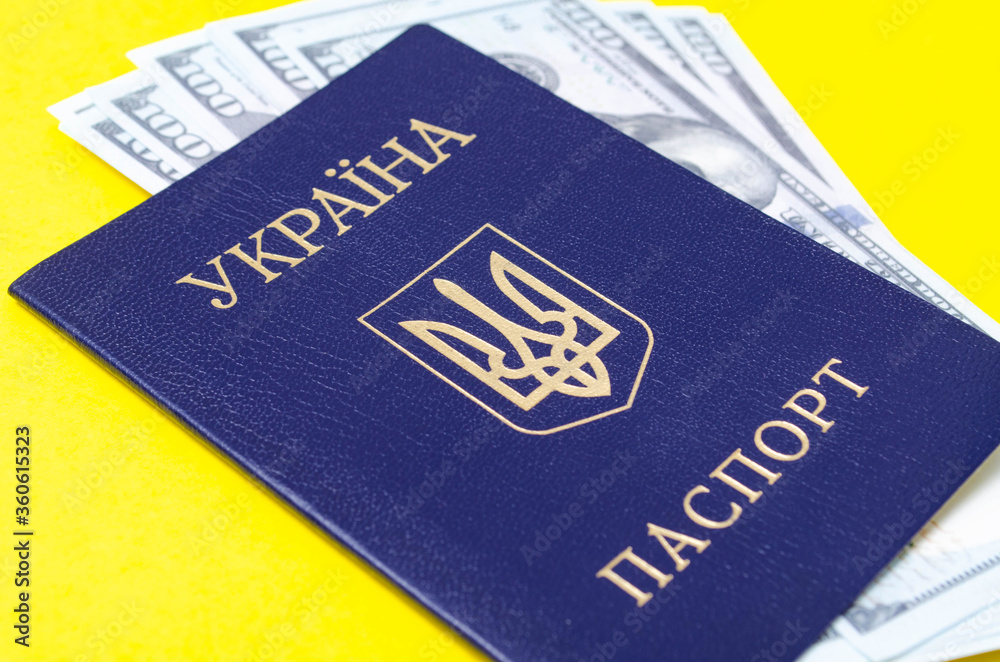 Ukrainian passport on a yellow background. $ 100 dollars are inside the passport at different angles Ukrainian passport on a yellow background. $ 100 dollars are inside the passport at different angles
